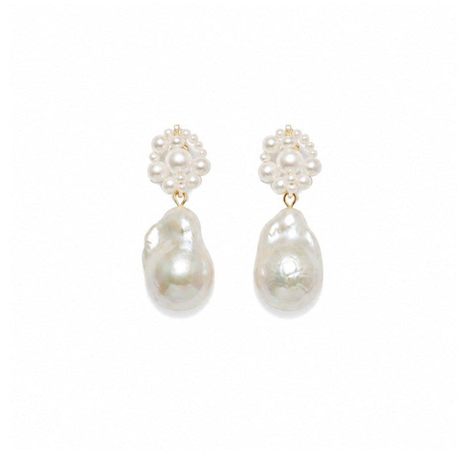 A pair of gold and pearl drop earrings featuring a small cluster of white pearls at the top and a larger, irregular baroque pearl dangling below, set against a plain white background.