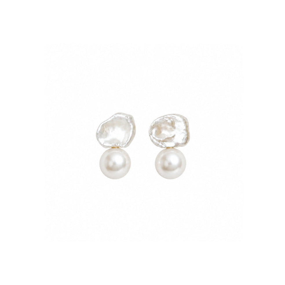 A pair of white stud earrings featuring one irregular keshi pearl and one smooth round pearl, set against a plain white background.