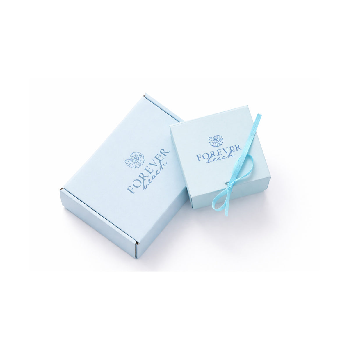 Two light blue product boxes with the brand name 'FOREVER beach' printed in blue on the lid, one larger rectangular box and one smaller square box tied with a matching blue ribbon, set against a plain white background.